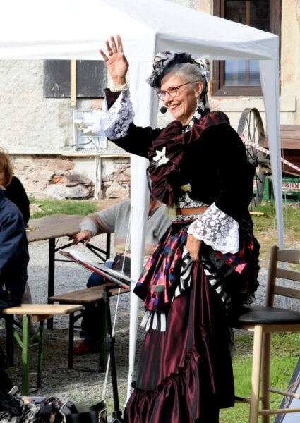 Biggi Hopp als Lady Bi winkt